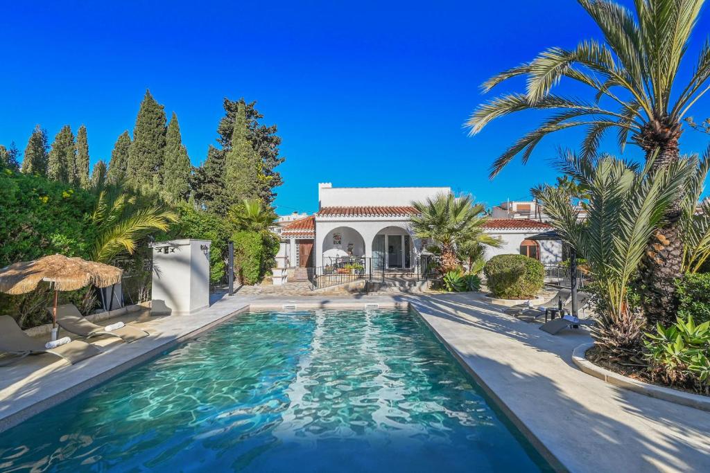 a swimming pool in front of a house with palm trees at Villa La Font with pool and bbq in Alicante