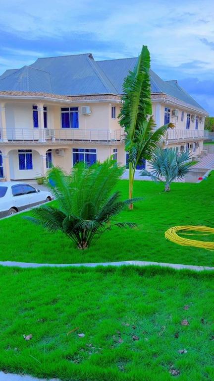 a large building with palm trees in front of a yard at ANITHA EXECUTIVe LODGE in Kibaha