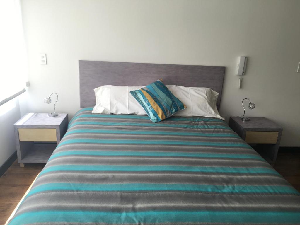 1 dormitorio con 1 cama grande y 2 mesitas de noche en Apartamento Finlandia Park Suite, en Quito