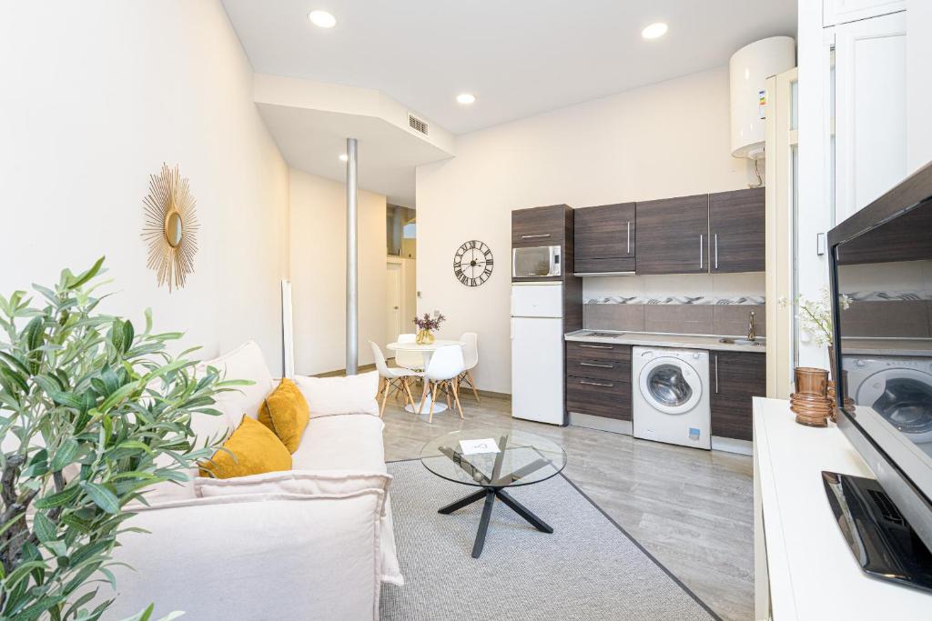 a living room with a white couch and a table at Apartamentos Calle Larios in Málaga