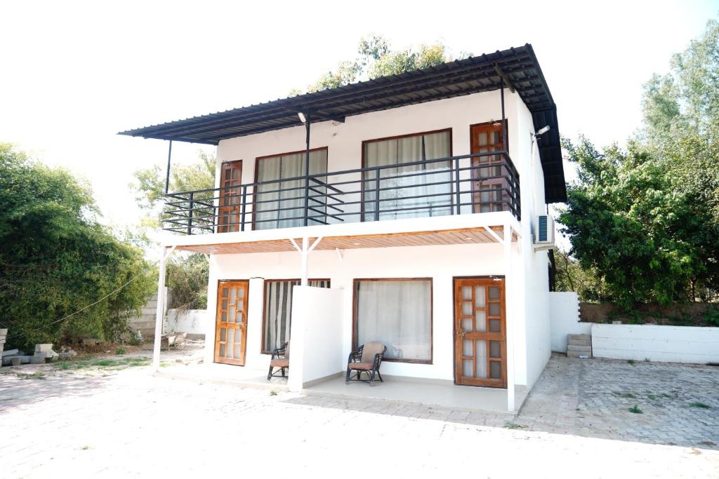 a white house with a balcony on top of it at Badrika Farm's in Rewa
