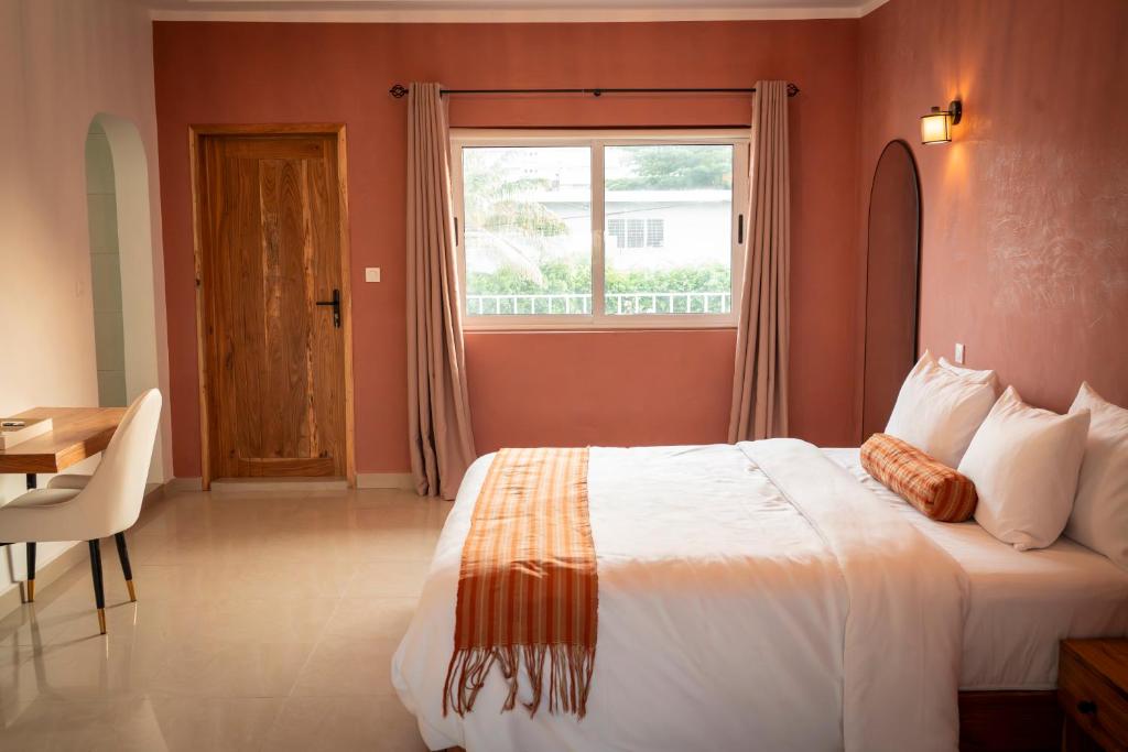 a bedroom with a large bed and a window at Résidence L'Eau Vive in Cotonou