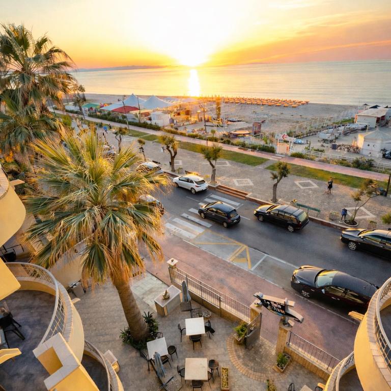 a city with cars parked in a parking lot with the sunset at La Baia Di Ulisse in Venetico