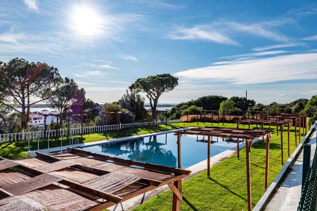 an image of a swimming pool with grass and a fence at Atlantic View Apartment-El Rompido in El Rompido