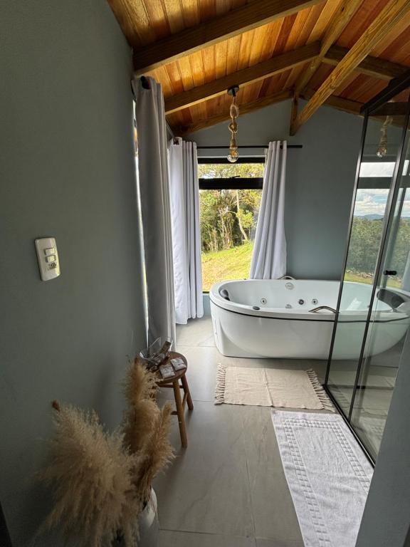 a bathroom with a bath tub and a window at Eco Tiny Latitude 28 in Urubici
