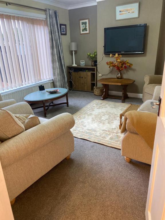 a living room with couches and a flat screen tv at Gramhor House in Dumfries