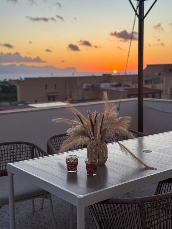 a white table with a plant on a balcony with a sunset at Casa Lo Bianco in Terrasini
