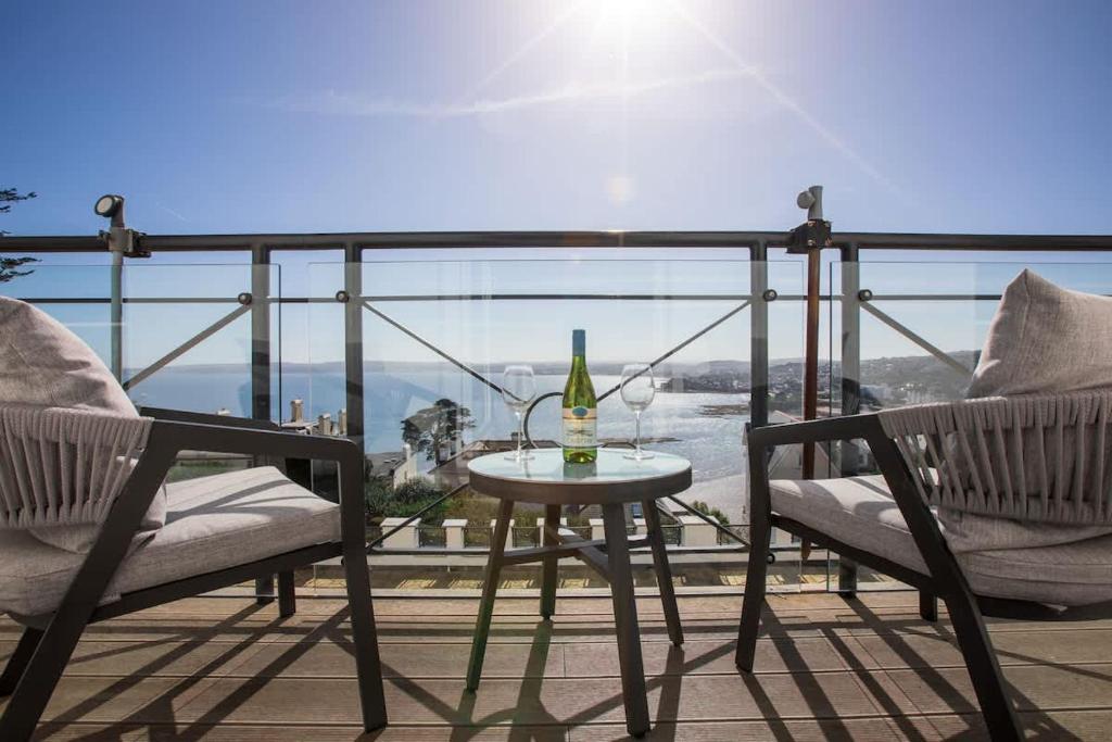 a table with a bottle of wine and two chairs on a balcony at Breathtaking Views at The Bay in Torquay