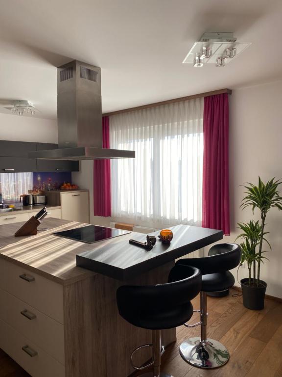 a kitchen with a island with black bar stools at Bright & Cozy Apartment in Villach
