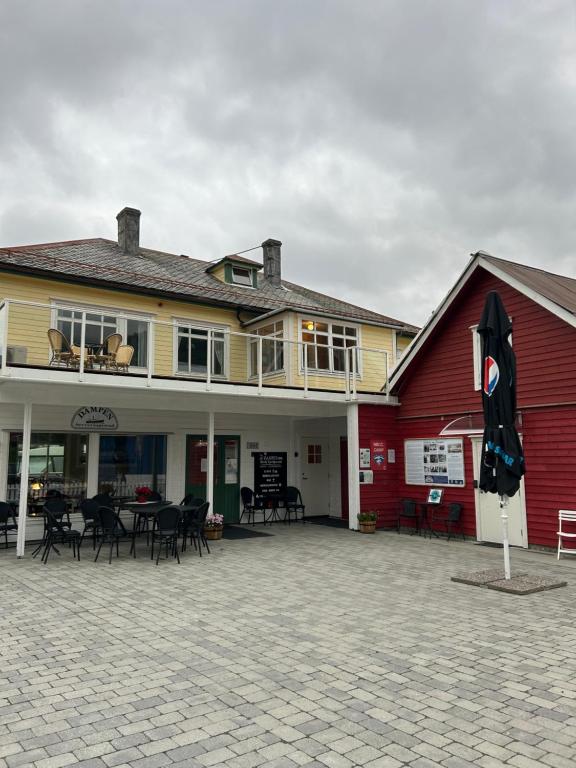a red and yellow building with tables and chairs at Davik Fjordparadis in Bakken