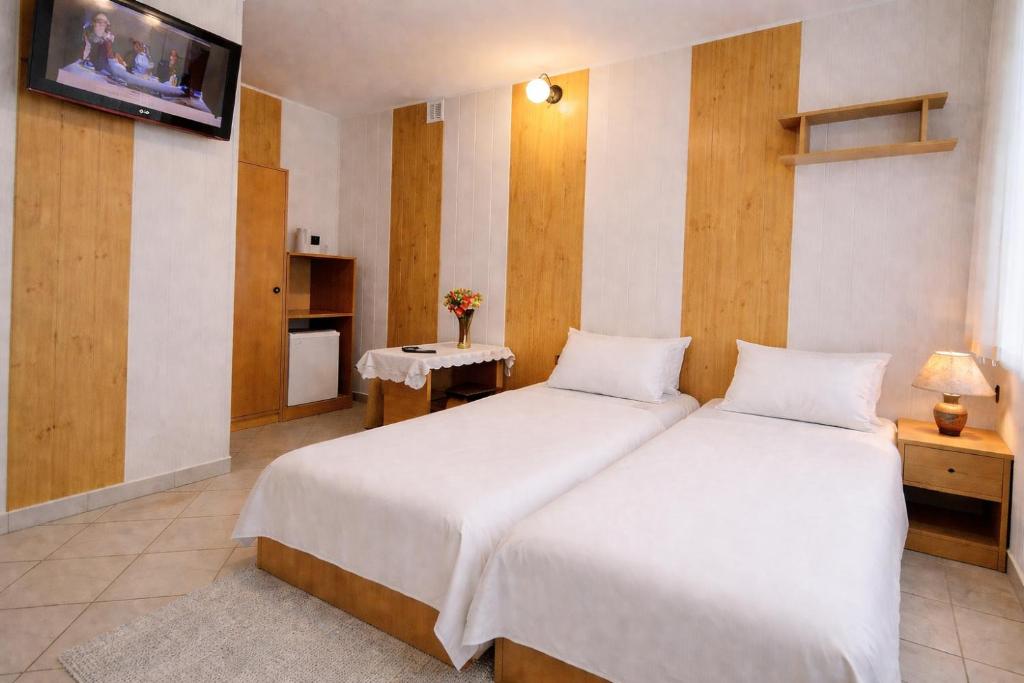 a bedroom with two beds and a tv on the wall at Nella - Pokoje gościnne in Ostrowo