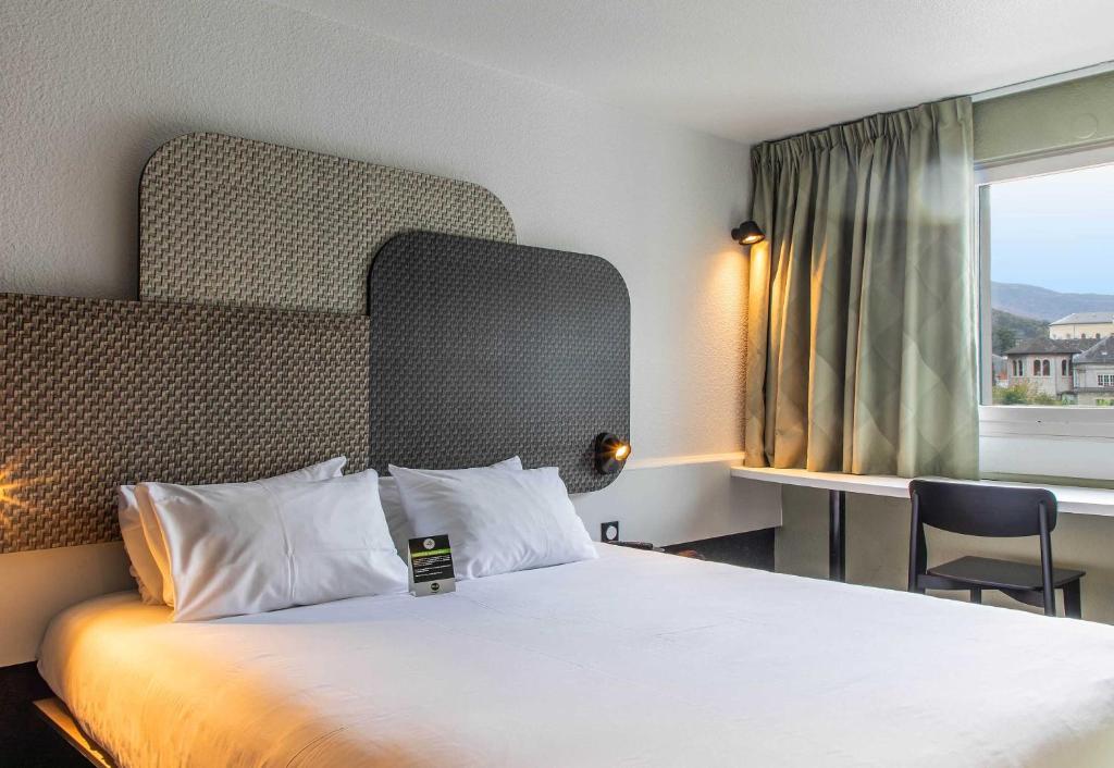 a hotel room with a bed and a window at B&B HOTEL Lourdes Centre Gare 3 étoiles in Lourdes