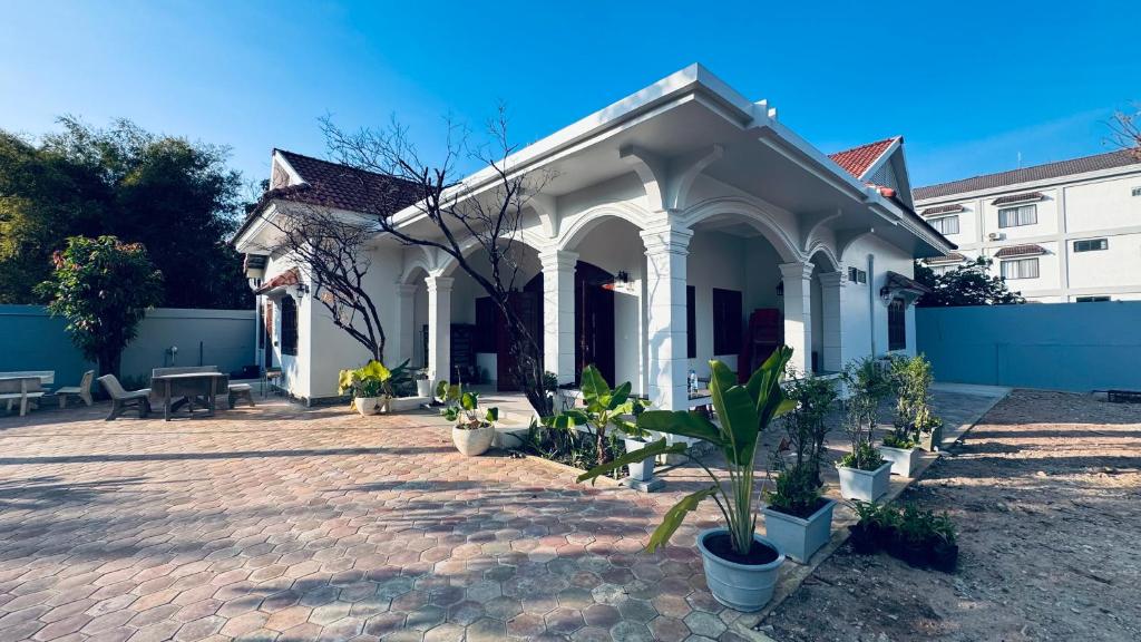 a white house with potted plants in a courtyard at Spacious Siem Reap Sanctuary in Phumi Ta Phul
