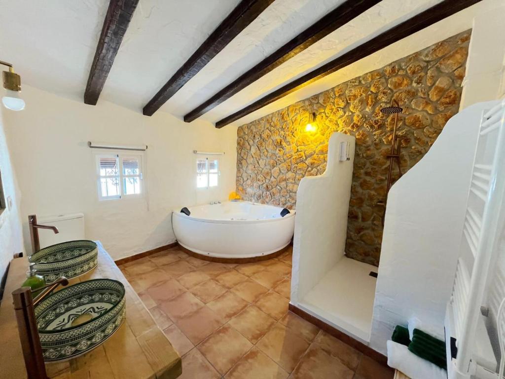a bathroom with a tub and a stone wall at La Casa del Pastor 1890 in Benaocaz
