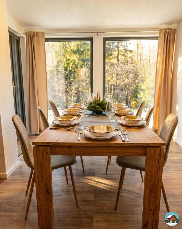 a wooden dining room table with chairs and a large window at Chata Hrbánik Tále in Bystrá