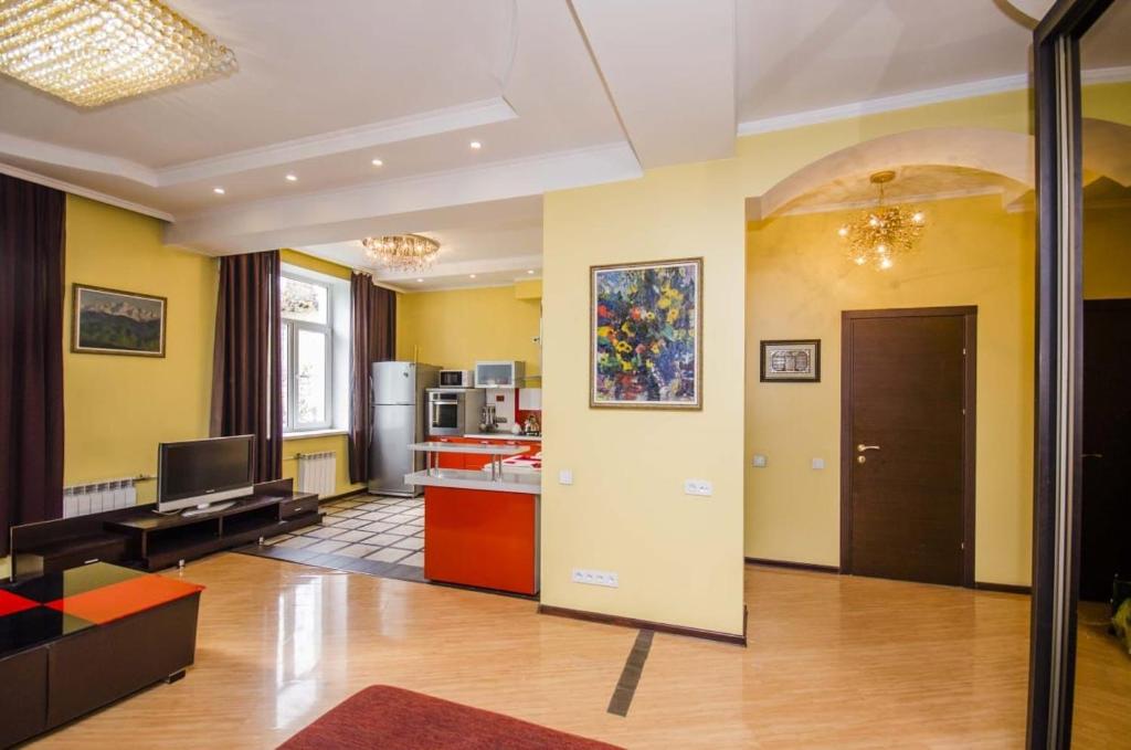 a living room with yellow walls and a kitchen at Abylai Khan 113 Central in Almaty