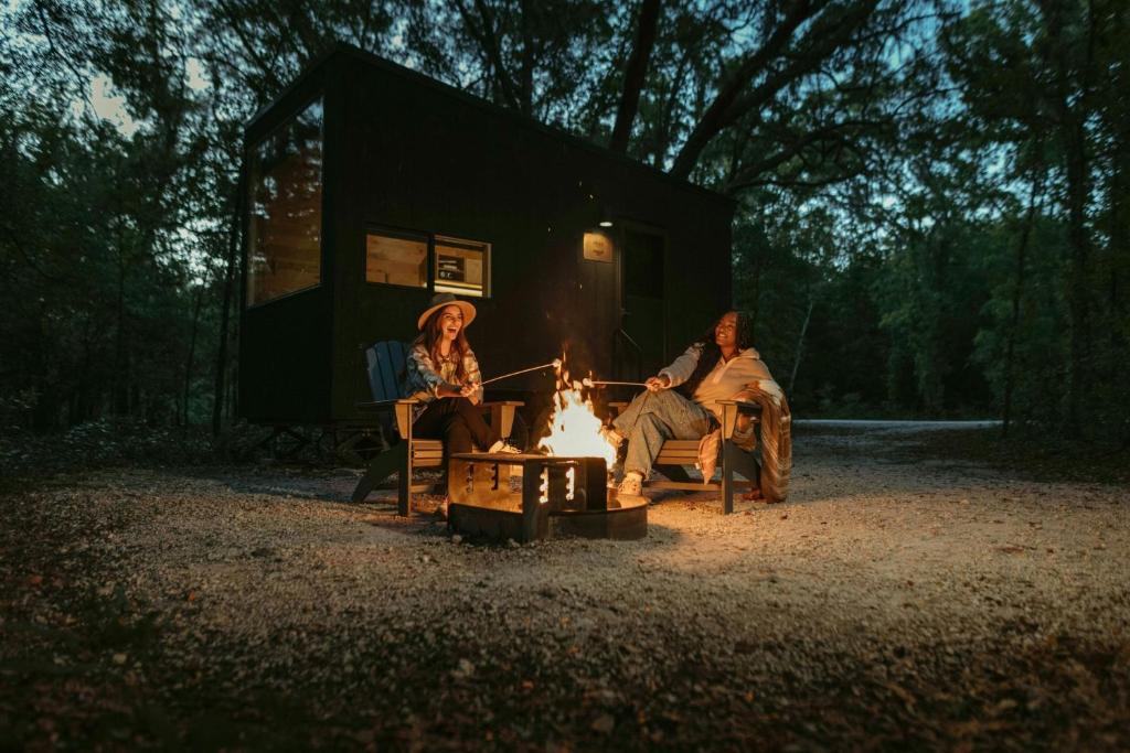 a couple of people sitting around a fire in front of a trailer at Postcard Cabins Barber Creek, Outdoor Collection by Marriott Bonvoy in Grand Junction