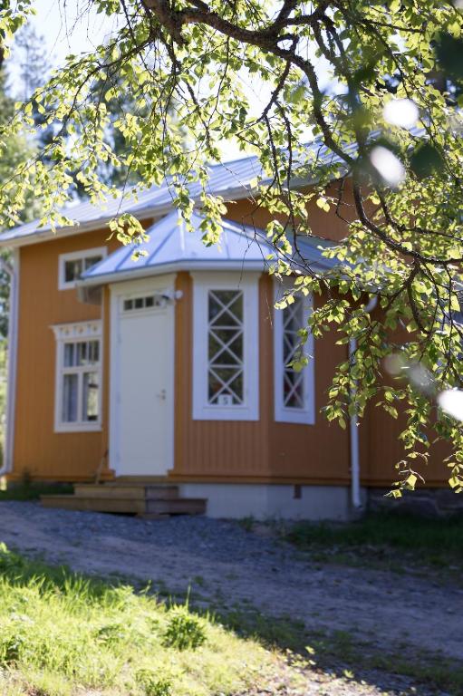 a small yellow house with a white door at Sundholms Gård - Sundholmin Tila in Kokkola