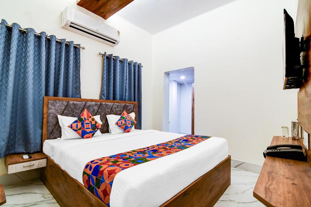 a bedroom with a large bed with blue curtains at FabHotel Adhiraj Inn in Kolkata