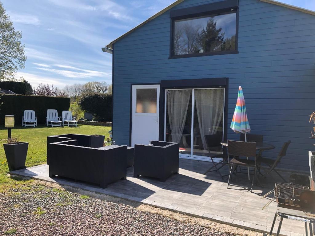 a blue house with a patio with a table and chairs at Gîtes Matignon 6 personnes in Matignon