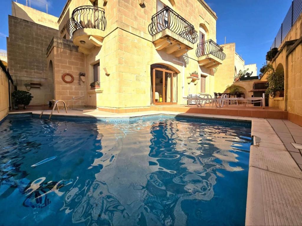 a swimming pool in front of a building at Ta Carmen Farmhouse with pool in Qala
