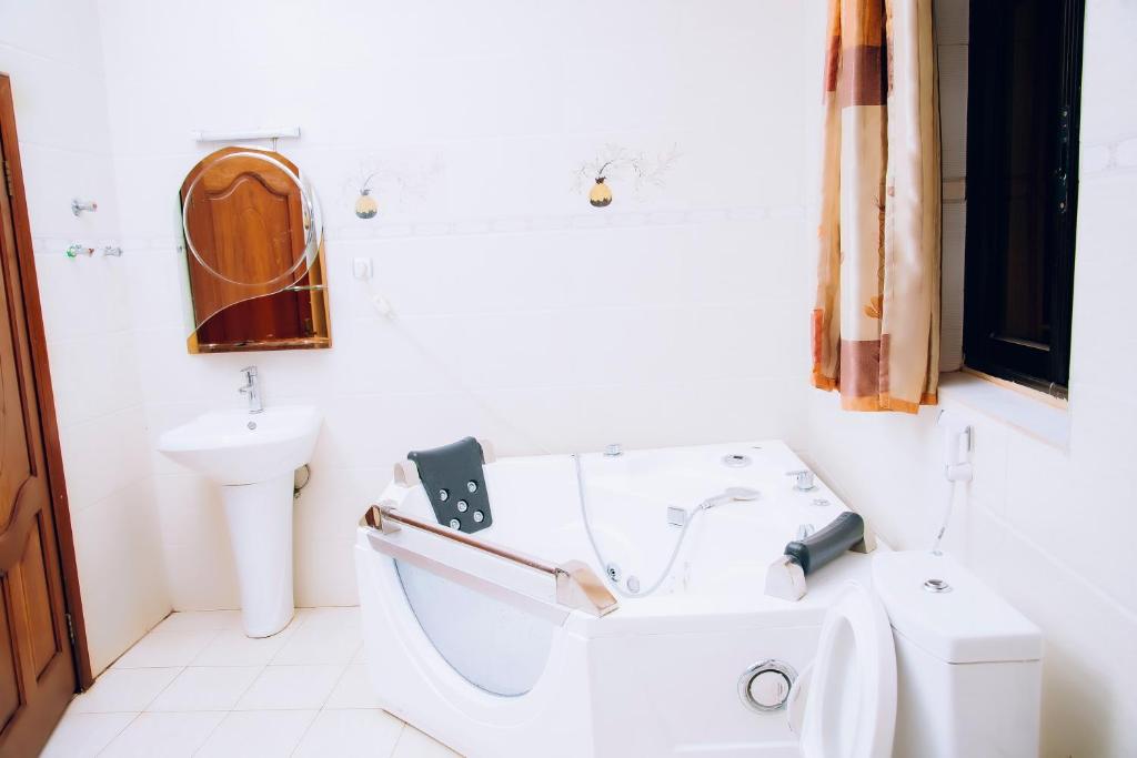 a white bathroom with a toilet and a sink at Stella nova motel in Kigali