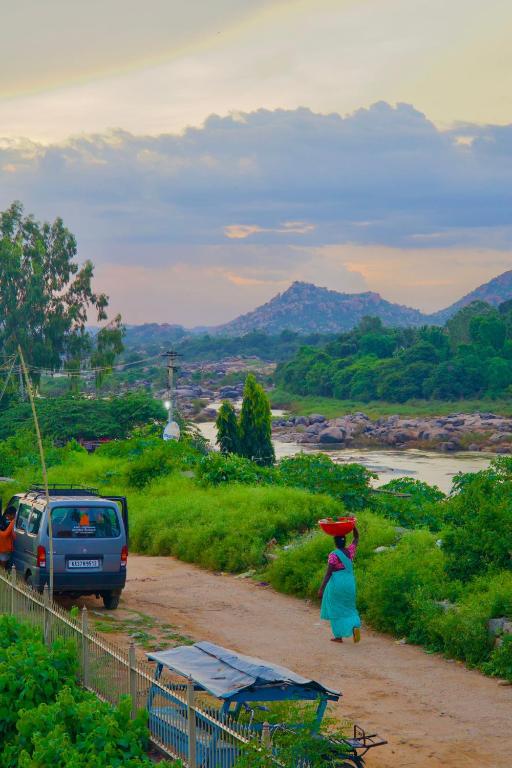 a woman walking down a dirt road with a frisbee at Funky monkey Home stay in Hampi