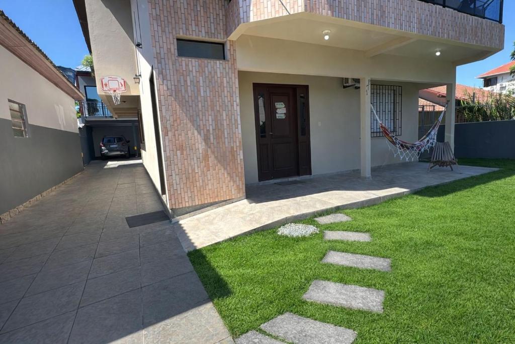a house with a lawn in front of a building at Mare Mansa Residence in Florianópolis
