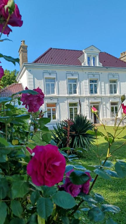 a large white house with pink flowers in front of it at La Carte Postale in Oye-Plage