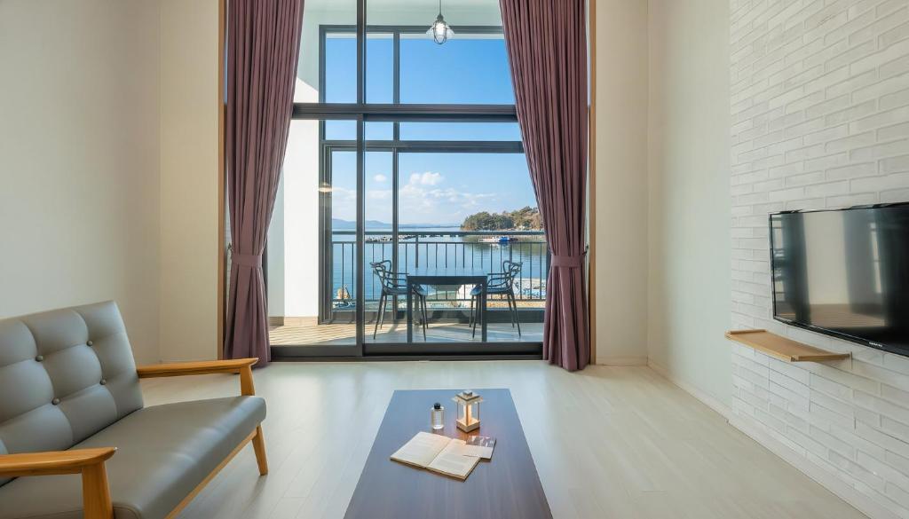 a living room with a couch and a television at Yeosu Arungeorida Ocean View Pension in Yeosu