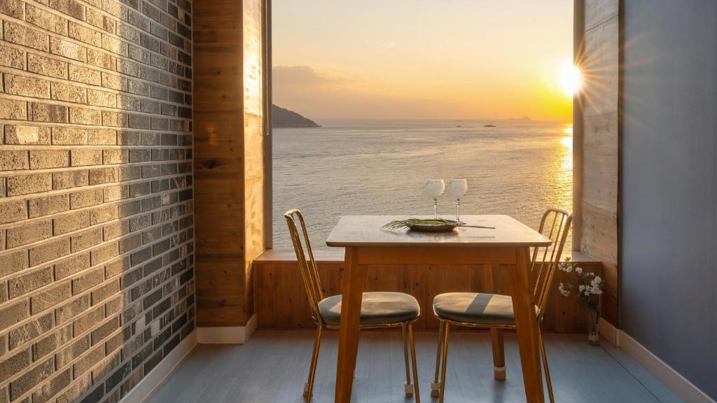 a table and chairs on a balcony with a view of the ocean at Geoje Inbito Pension in Op'o