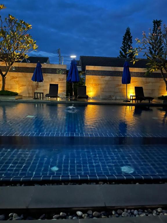 a pool with chairs and umbrellas at night at Wilfrid villa in Hua Hin