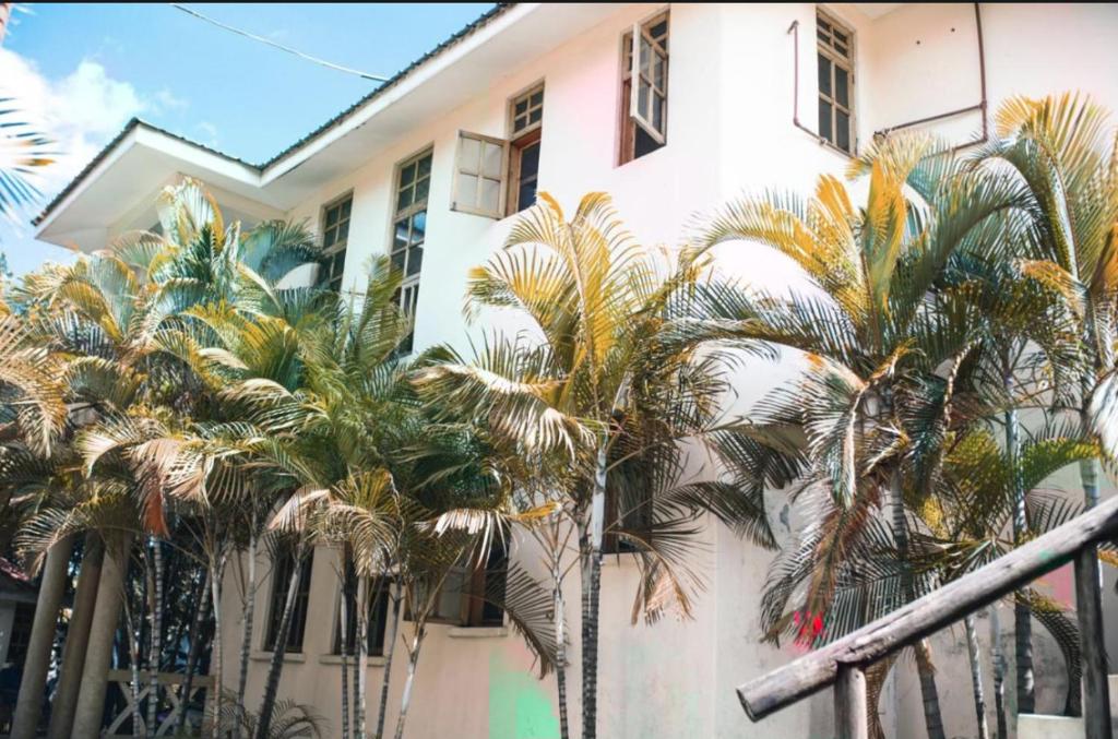 a group of palm trees in front of a building at The Paradise Inn Kilimanjaro in Moshi