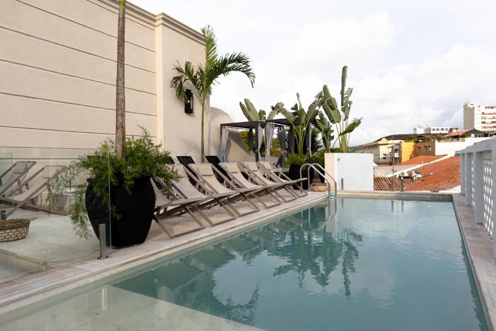 a swimming pool with lounge chairs next to a building at Hotel Casa Bianca by Faranda Boutique in Cartagena de Indias