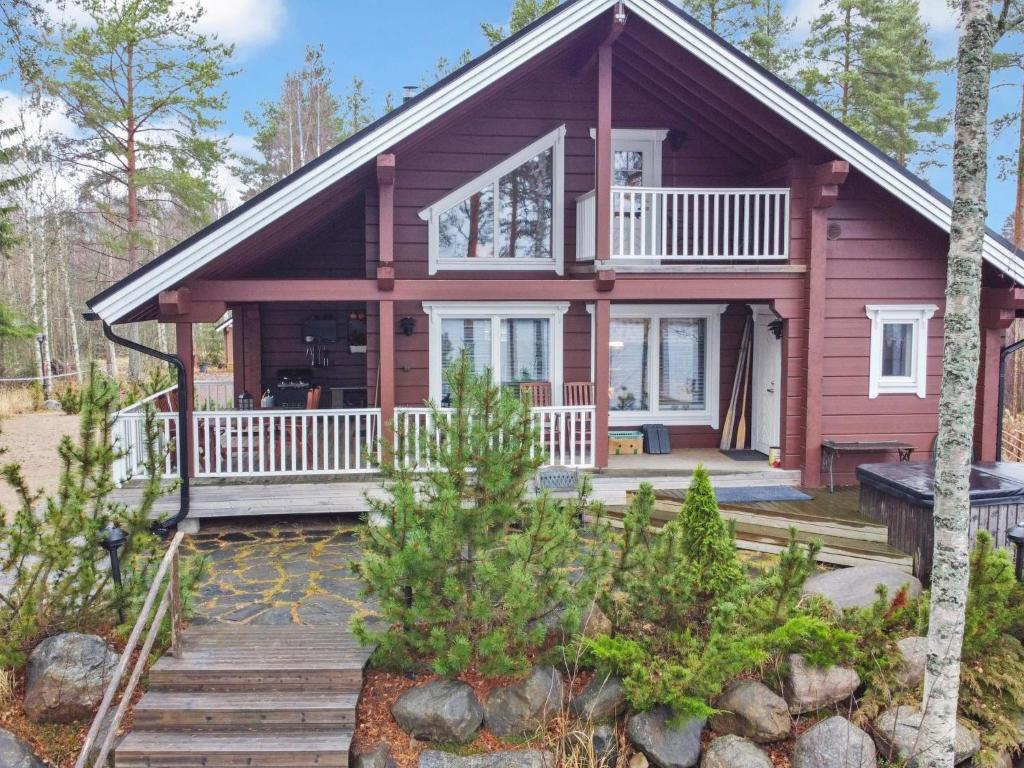 a cabin in the woods with a deck and a house at Holiday Home Loisteranta by Interhome in Vääräkoski
