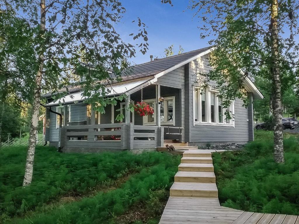 a small gray house with a porch and a wooden walkway at Holiday Home Kallentupa by Interhome in Ruka