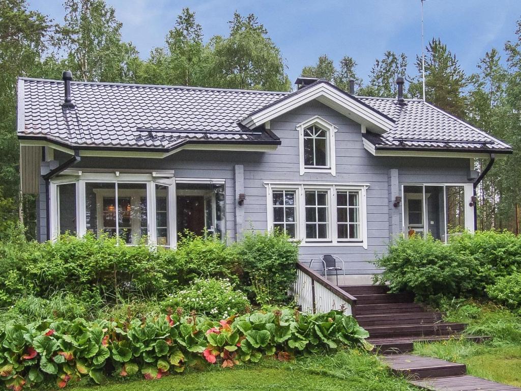a gray house with a porch and some bushes at Holiday Home Ojala by Interhome in Virta