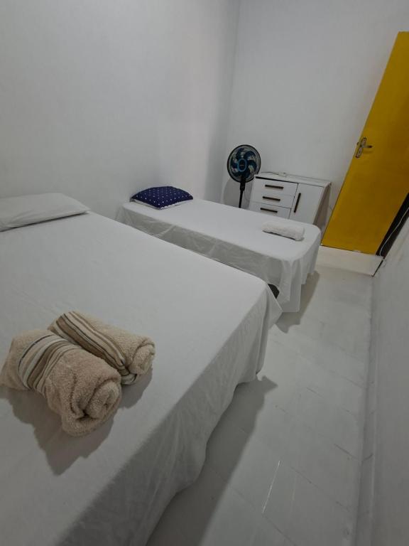 two beds in a white room with towels on them at CASA DE HOSPEDAGEM FLORES PARATY AMBIENTE FAMILIAR 600M do CENTRO in Paraty