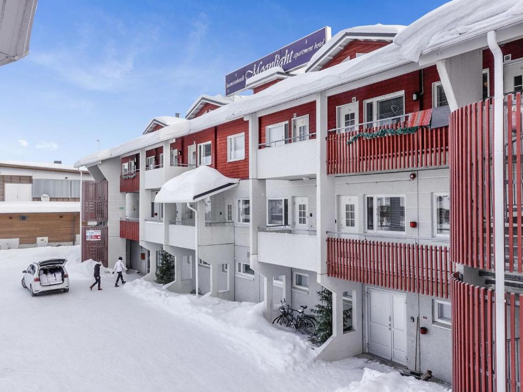two people walking in the snow in front of a building at Holiday Home Levin tuisku by Interhome in Levi