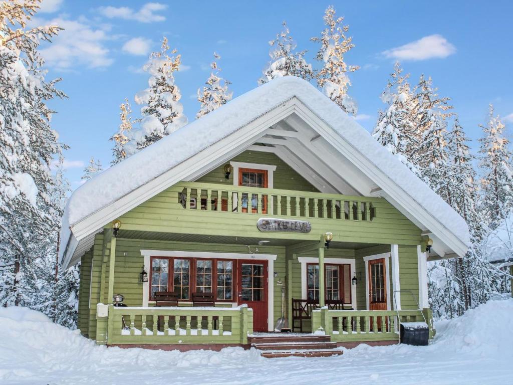 a small green house with a snow covered roof at Holiday Home Saikulevi by Interhome in Levi