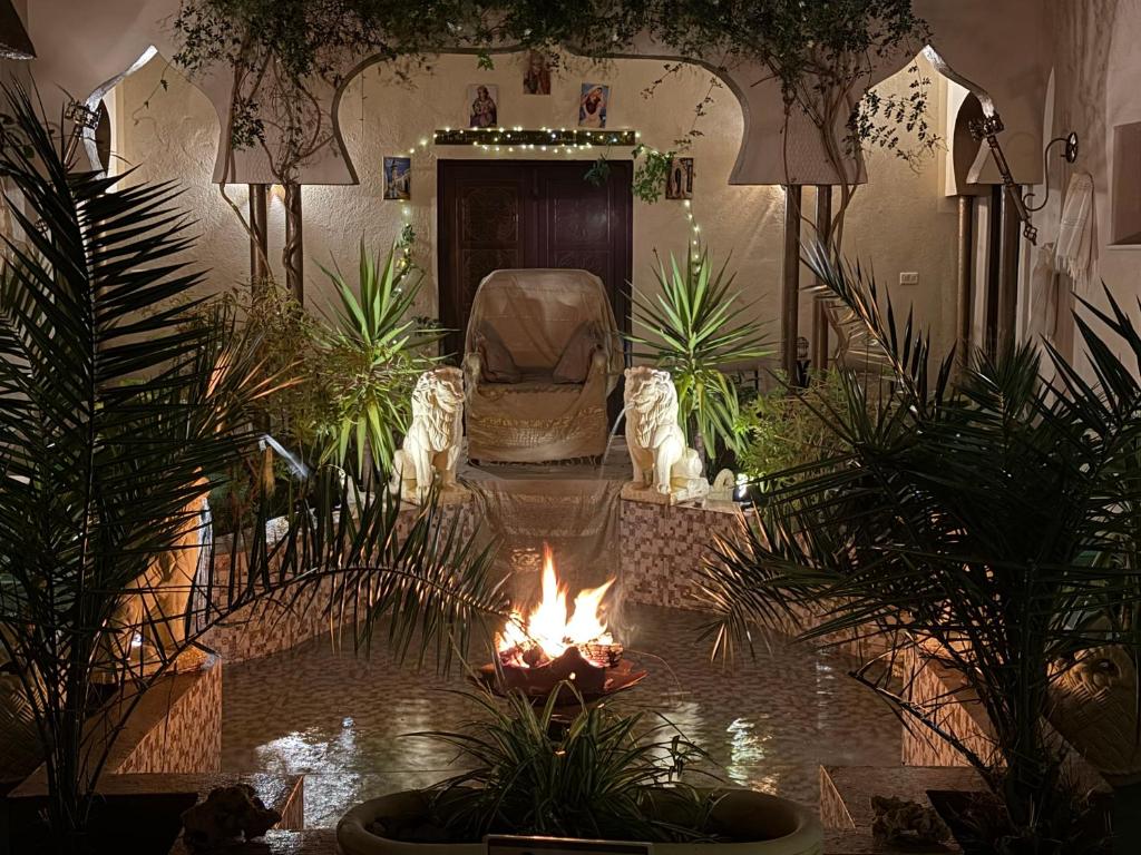 a living room with a fire in a room with plants at 1001-Nights Palace in Nebeur