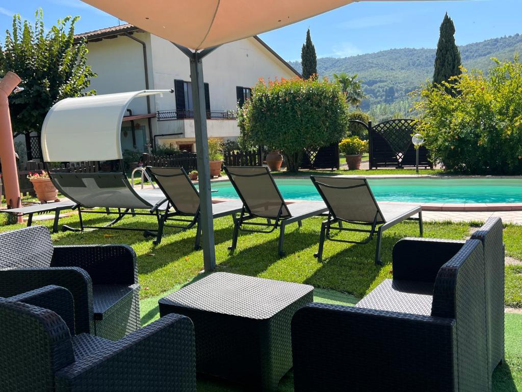 a group of chairs and an umbrella next to a pool at RelaxHomeHoliday in Panicale