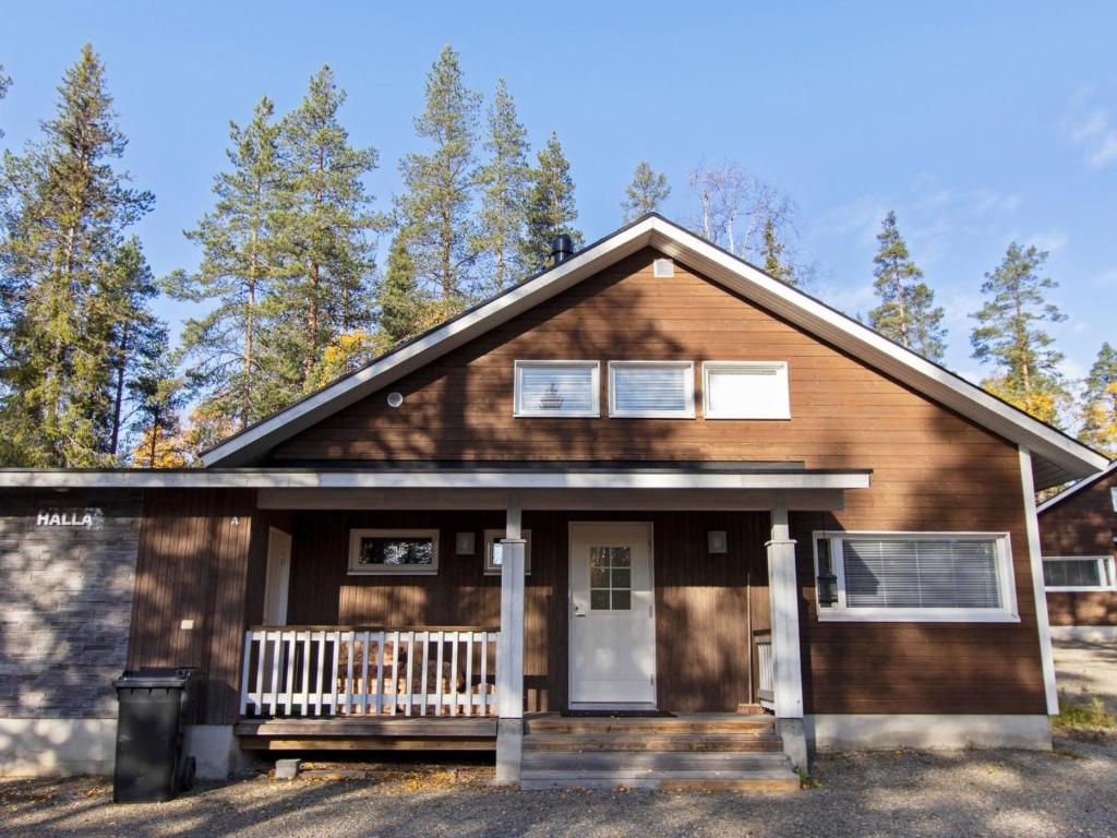 a wooden house with a front porch and trees at Holiday Home Halla by Interhome in Levi