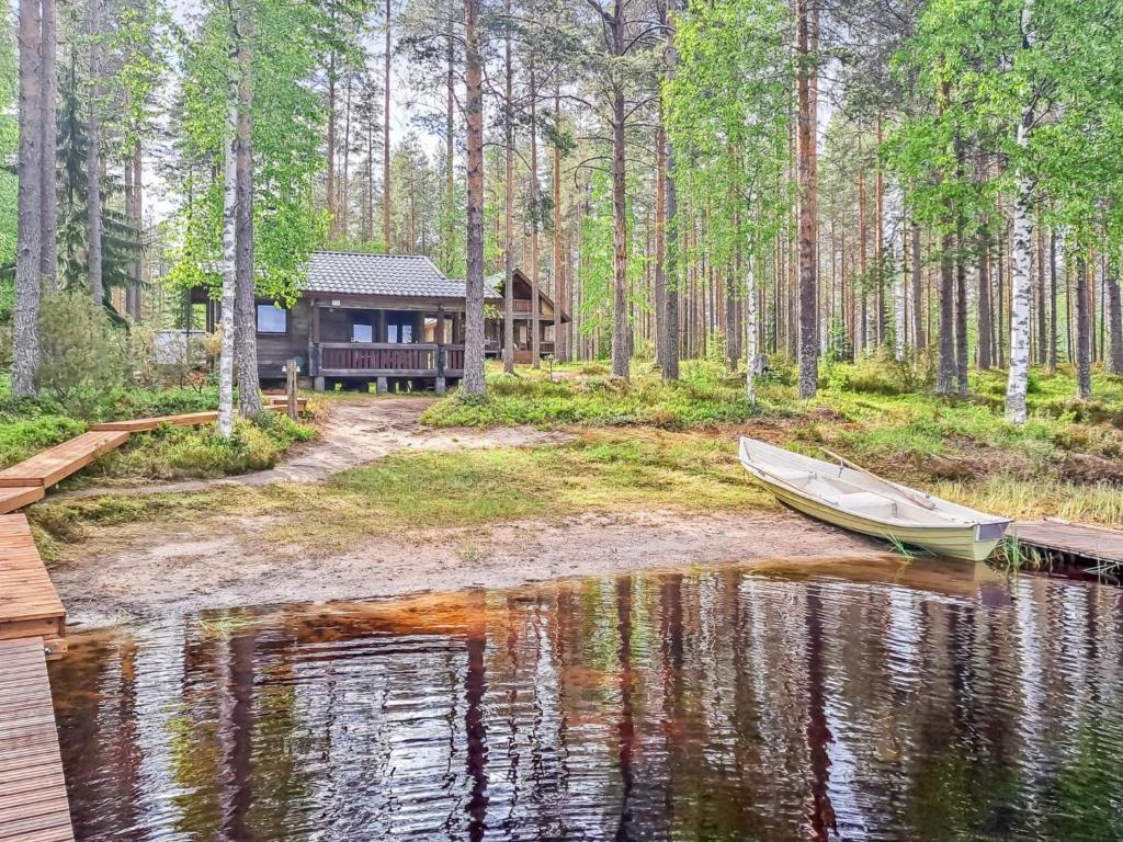 a boat is docked in front of a cabin in the woods at Holiday Home Pilkkaniemi by Interhome in Rontsa