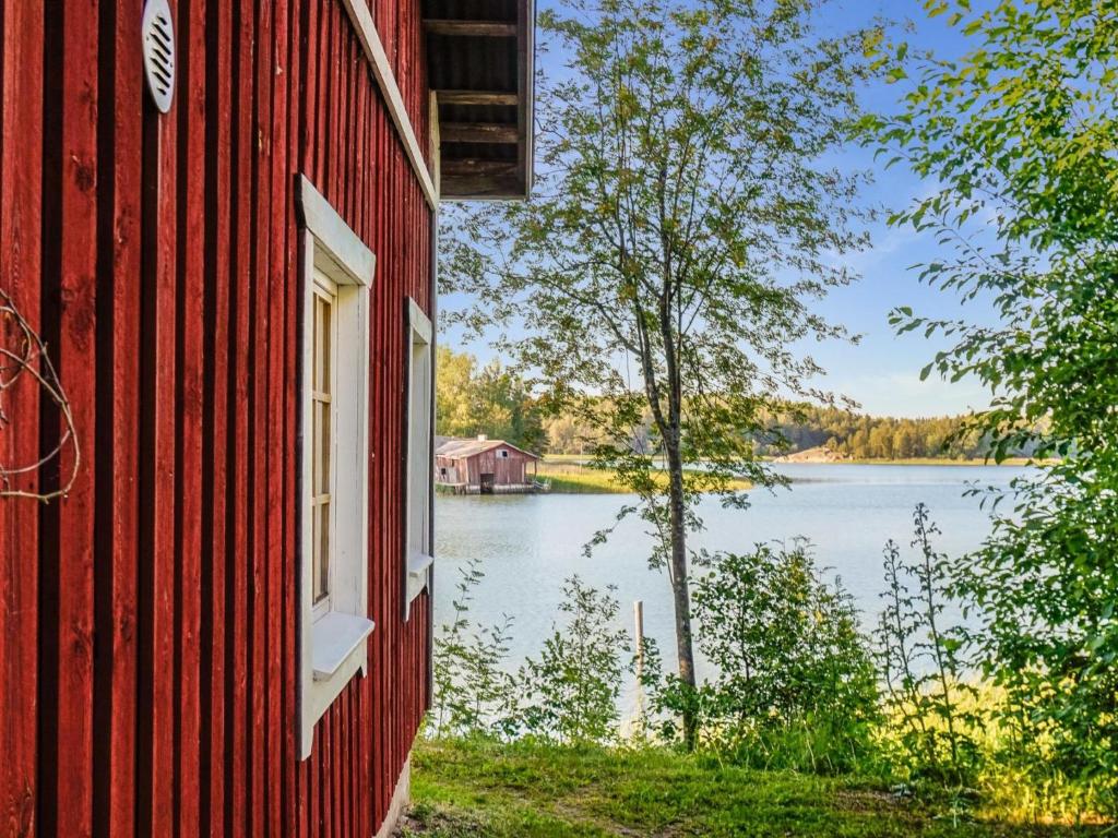 a red building with a view of a lake at Holiday Home Rantasipi 1 by Interhome in Strandby