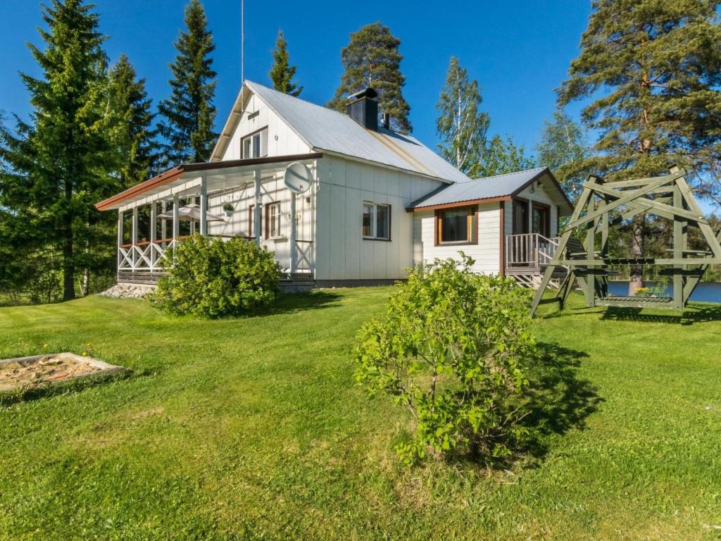 a white house on a grassy yard with a playground at Holiday Home Tarvas by Interhome in Tarvaspohja