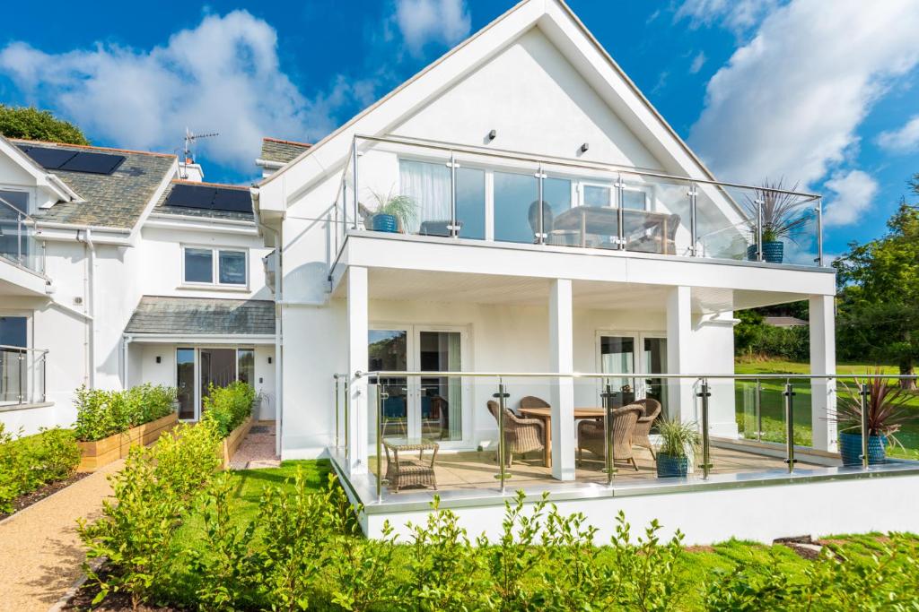 a white house with a balcony with a table and chairs at Thurlestone Retreats in Thurlestone