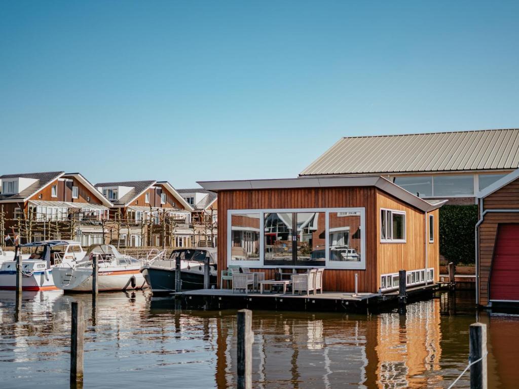 a house on a dock with boats in the water at Holiday Home De Woude by Interhome in Uitgeest