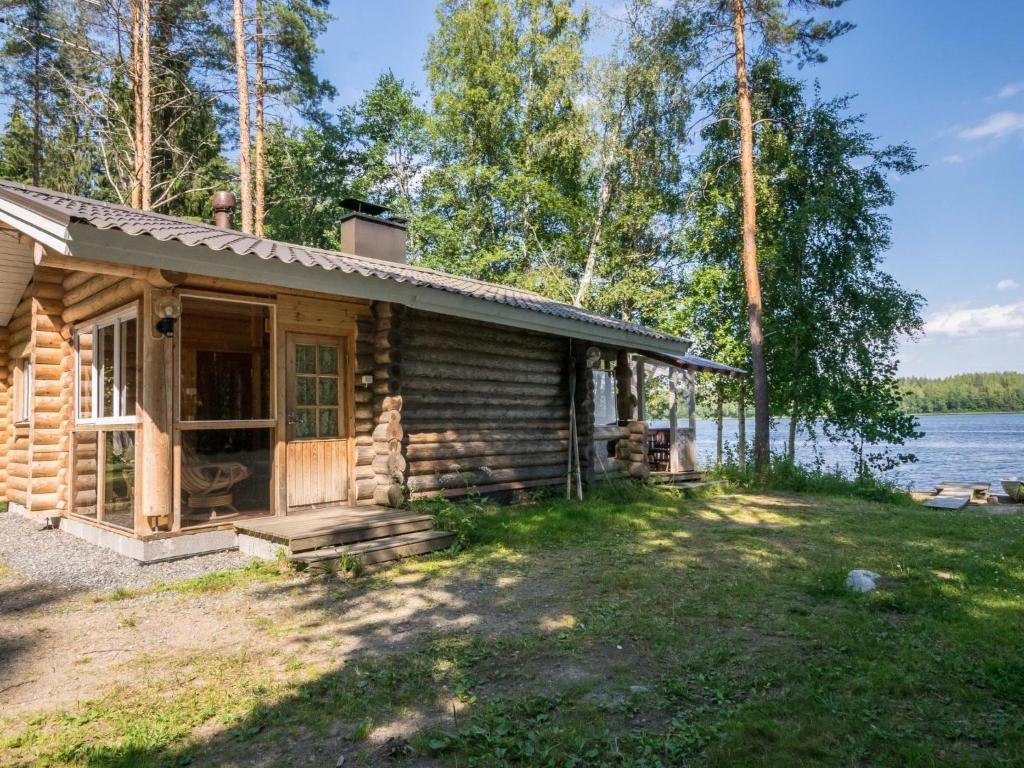 a log cabin with a porch and a lake at Holiday Home Lemmenmaja by Interhome in Paatela