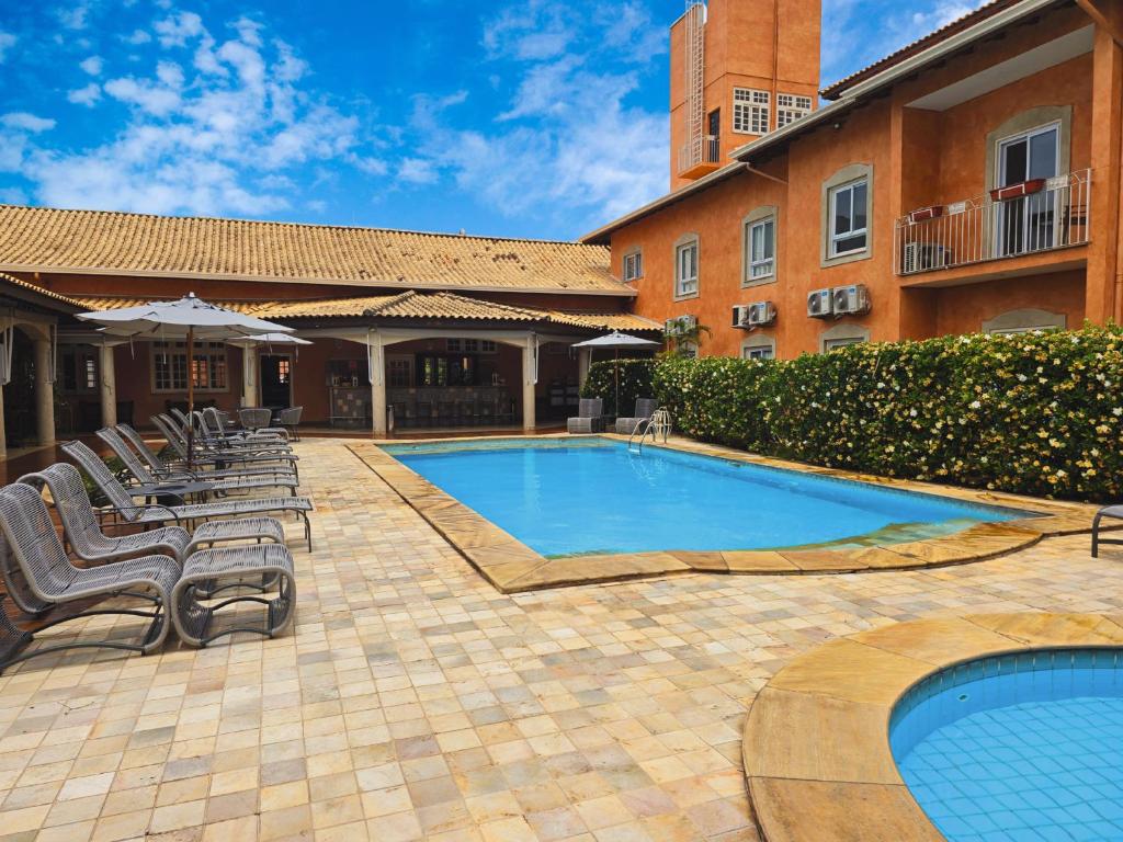 a swimming pool in a courtyard with chairs and a building at Hotel Cordialle in São Roque
